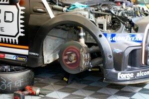 Close-up of race car undergoing maintenance in Silverstone, showing disc brake and tools.