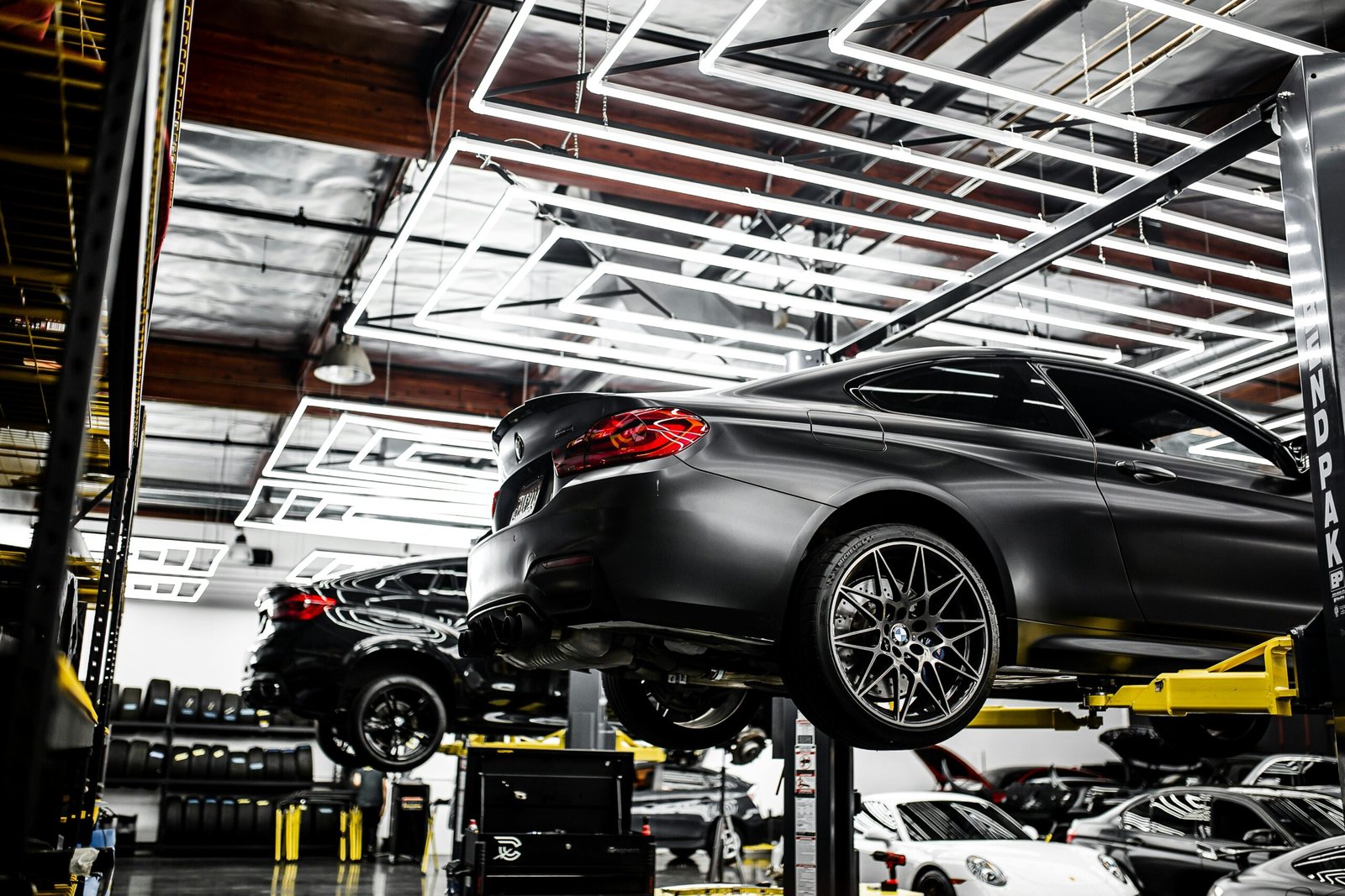 A modern car repair shop showcasing vehicles on lifts and a well-lit, organized interior.